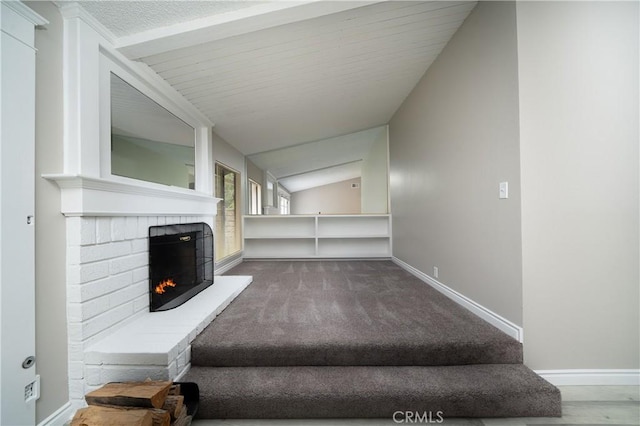 carpeted living area with baseboards, a fireplace, and vaulted ceiling