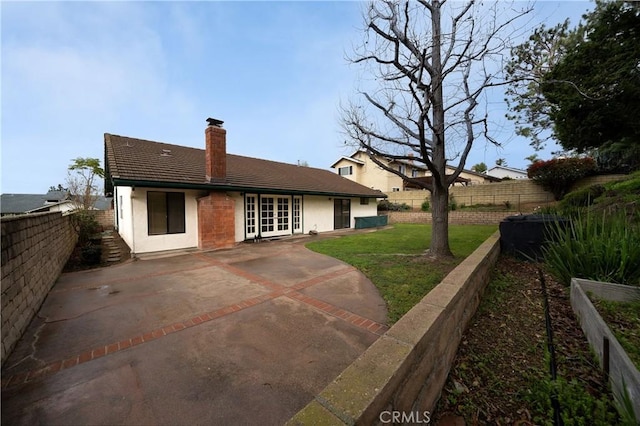 back of property featuring a patio area, a yard, a chimney, and a fenced backyard