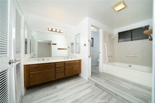 bathroom featuring bathing tub / shower combination, toilet, wood finished floors, and a sink