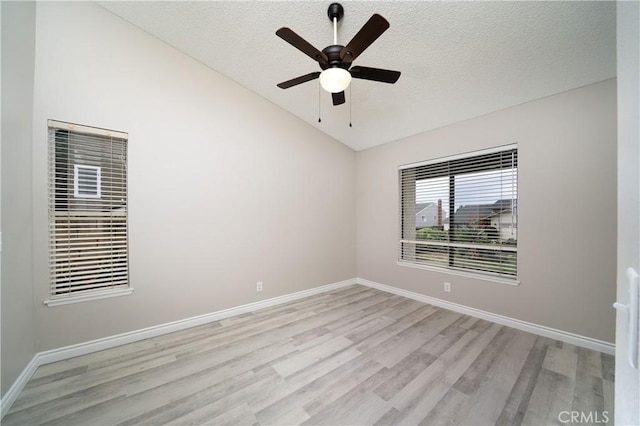 unfurnished room with a textured ceiling, baseboards, light wood-style floors, and vaulted ceiling