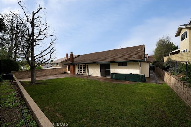 rear view of property featuring a patio, a lawn, and a fenced backyard