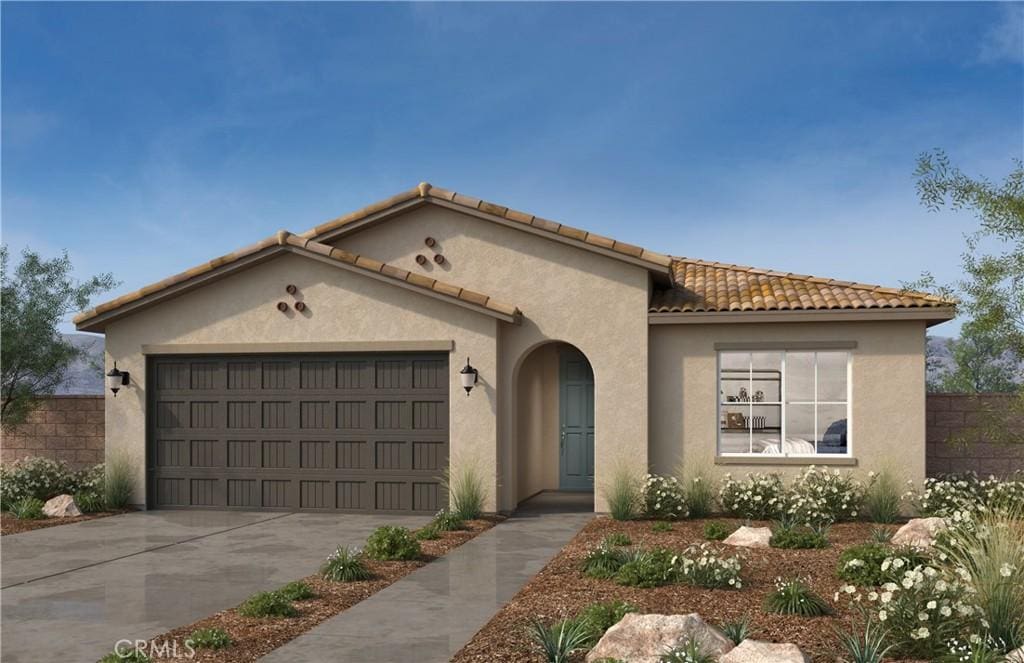 mediterranean / spanish house featuring stucco siding, an attached garage, concrete driveway, and fence