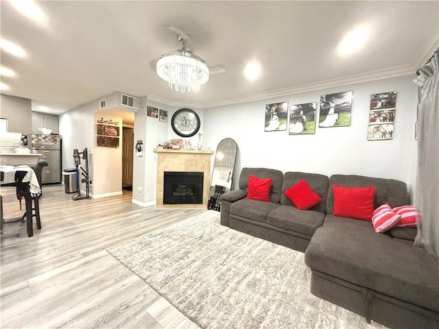 living room with light wood finished floors, visible vents, baseboards, ornamental molding, and a fireplace