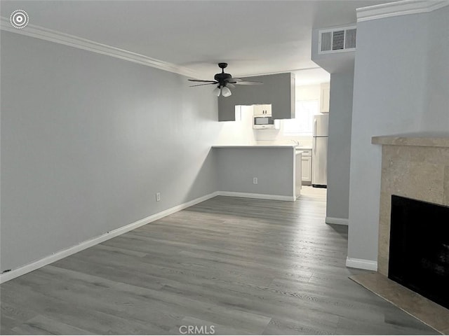 unfurnished living room featuring visible vents, wood finished floors, a fireplace, crown molding, and baseboards