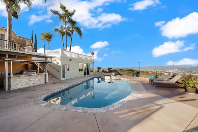 view of swimming pool featuring a pool with connected hot tub, exterior kitchen, and a patio area