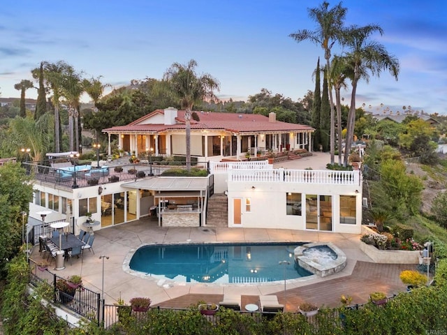 rear view of house featuring a patio, a pool with connected hot tub, outdoor dry bar, and fence