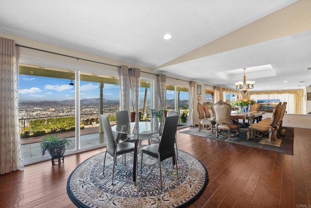 dining space with a tray ceiling, recessed lighting, hardwood / wood-style flooring, a notable chandelier, and a mountain view