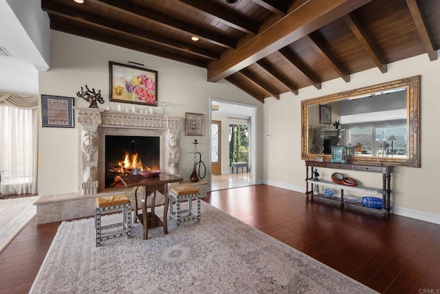 living area with baseboards, vaulted ceiling with beams, hardwood / wood-style floors, and a high end fireplace