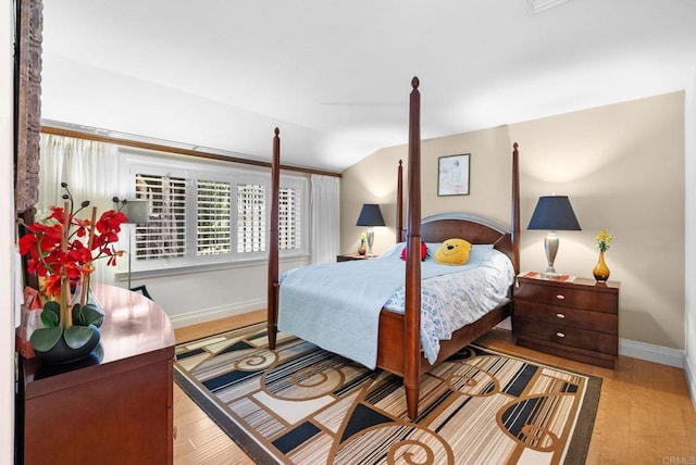 bedroom featuring baseboards, wood finished floors, and vaulted ceiling