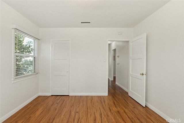 unfurnished bedroom featuring visible vents, baseboards, and wood finished floors