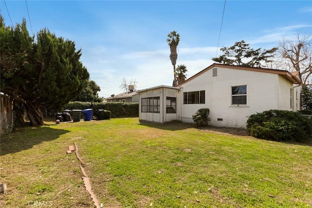 back of property with crawl space, stucco siding, a lawn, and fence