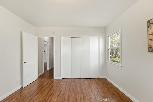 unfurnished bedroom with light wood-style floors, baseboards, and a closet