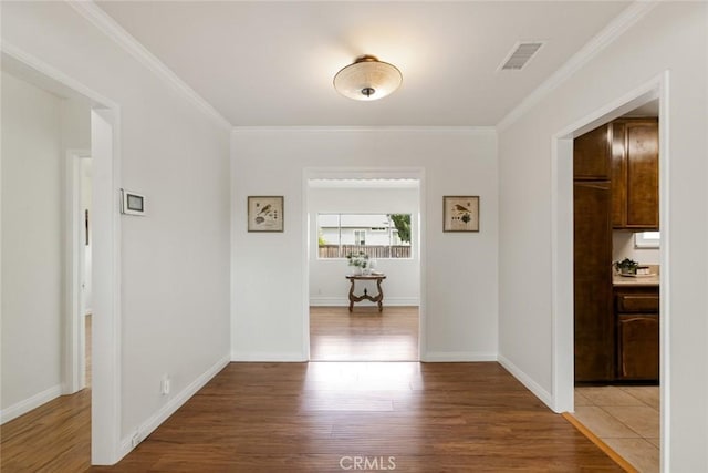 corridor featuring visible vents, ornamental molding, and wood finished floors