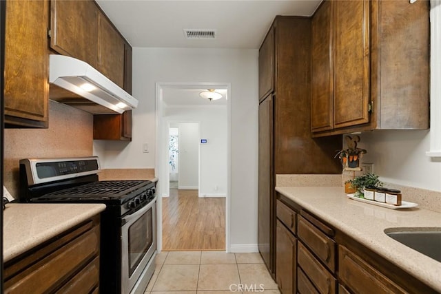 kitchen featuring visible vents, stainless steel range with gas cooktop, under cabinet range hood, light countertops, and light tile patterned floors