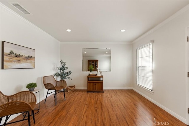 living area featuring visible vents, crown molding, baseboards, recessed lighting, and light wood-style flooring