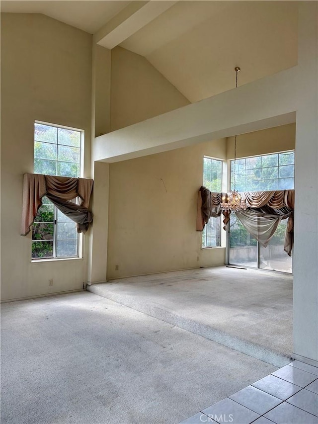 tiled spare room featuring carpet flooring, a chandelier, and high vaulted ceiling