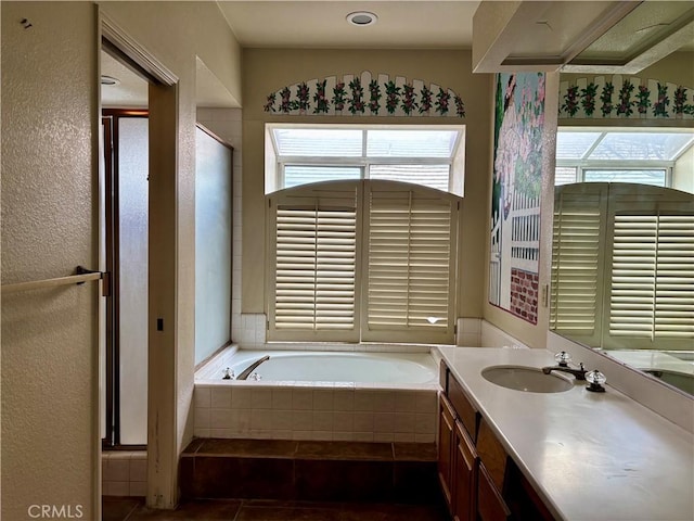 full bathroom with tile patterned flooring, a stall shower, a textured wall, a bath, and vanity