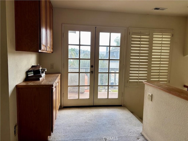 entryway with visible vents, light carpet, and french doors