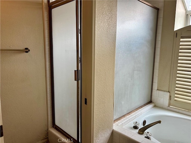 bathroom with a bath, a shower stall, and a textured wall