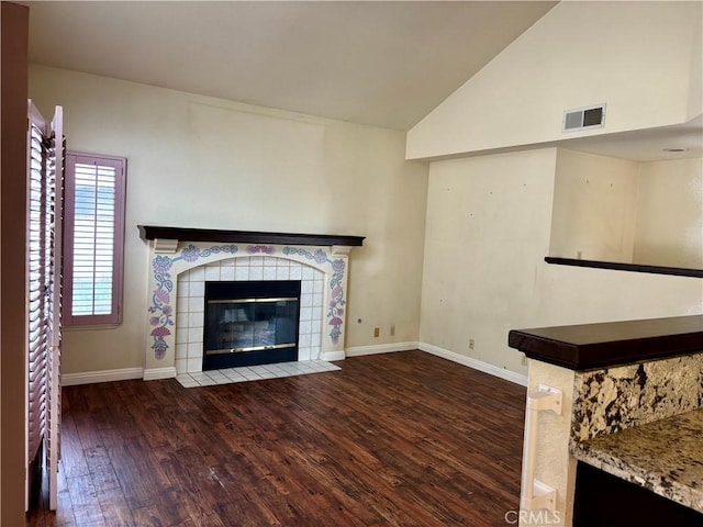 unfurnished living room featuring visible vents, baseboards, a tiled fireplace, vaulted ceiling, and wood finished floors