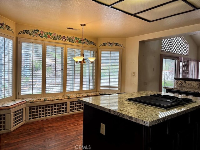 kitchen featuring visible vents, a healthy amount of sunlight, dark wood-type flooring, stovetop with downdraft, and a textured ceiling