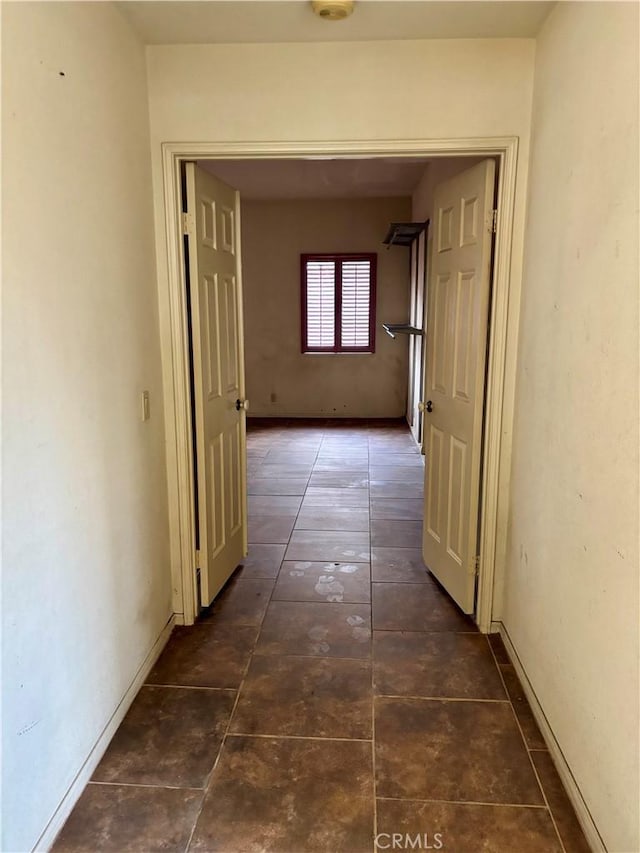 hallway featuring tile patterned floors and baseboards