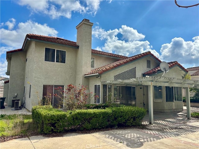 rear view of house featuring stucco siding, a pergola, a patio, a chimney, and a tiled roof