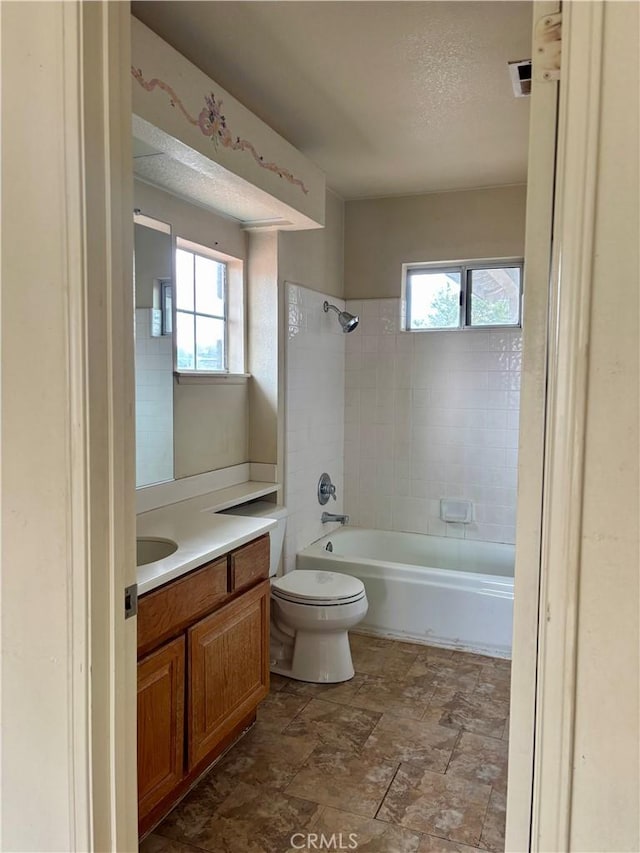 full bath with a textured ceiling, toilet, vanity, and  shower combination