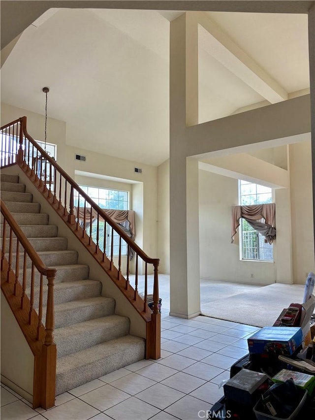 stairway featuring tile patterned floors, visible vents, arched walkways, and high vaulted ceiling