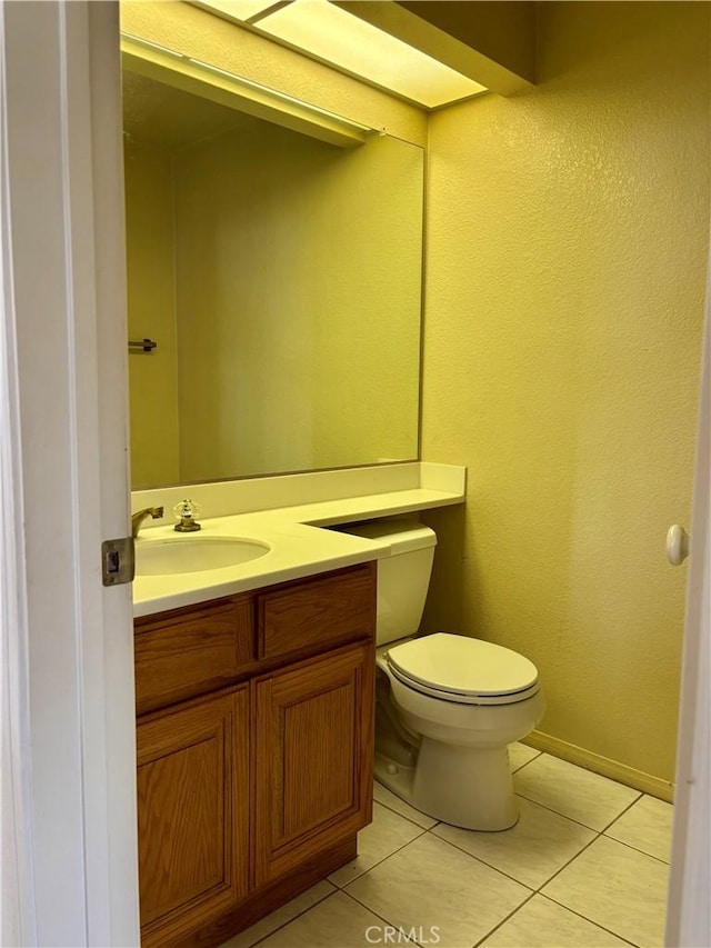 half bath featuring tile patterned floors, toilet, and vanity