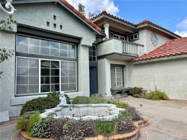 entrance to property featuring stucco siding and a balcony