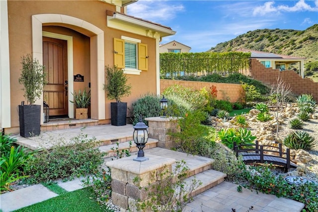 property entrance featuring stucco siding, a mountain view, and fence