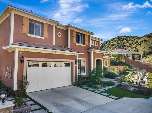 view of front of property featuring stucco siding, a garage, concrete driveway, and fence