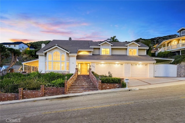 view of front of home with a gate, fence, concrete driveway, a garage, and brick siding