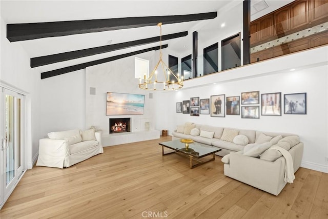 living room with light wood-type flooring, a lit fireplace, beam ceiling, an inviting chandelier, and high vaulted ceiling