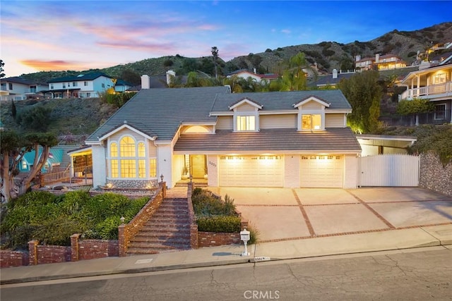 traditional-style house featuring a gate, a mountain view, concrete driveway, a garage, and a tiled roof