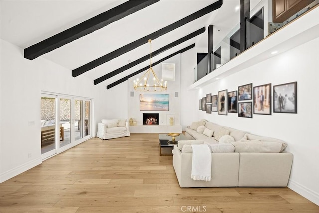 living area with beam ceiling, light wood finished floors, a lit fireplace, and high vaulted ceiling