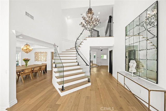 staircase featuring hardwood / wood-style floors, a high ceiling, visible vents, and a chandelier