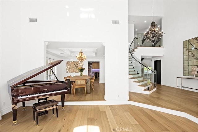 entryway featuring stairway, wood-type flooring, a notable chandelier, and visible vents