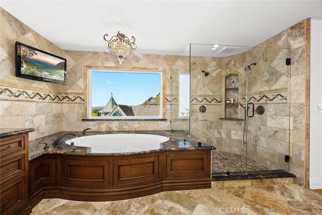 full bathroom with a shower stall, a garden tub, and a chandelier