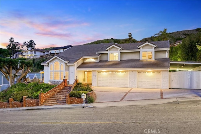 traditional-style home featuring brick siding, concrete driveway, a garage, and fence