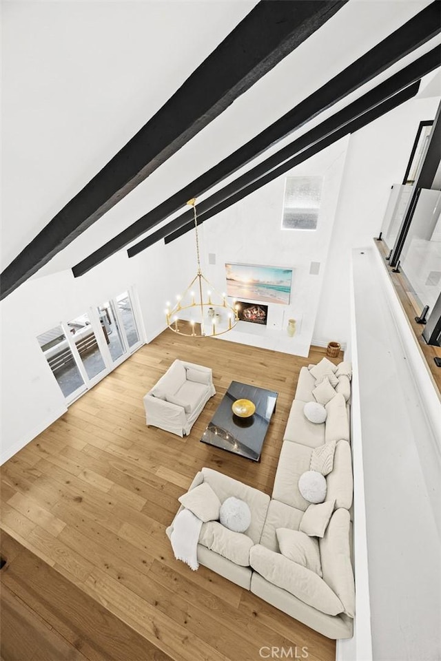 living room featuring wood finished floors, a chandelier, and vaulted ceiling with beams