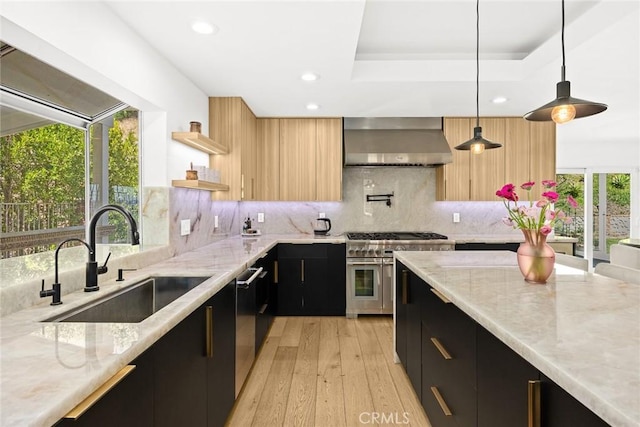 kitchen featuring a sink, stainless steel appliances, wall chimney range hood, modern cabinets, and dark cabinets