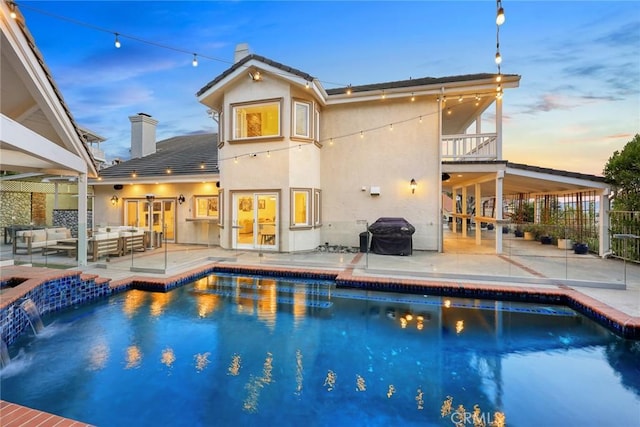 back of property featuring a balcony, stucco siding, a chimney, outdoor lounge area, and a patio area