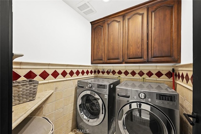 washroom featuring visible vents, a wainscoted wall, cabinet space, separate washer and dryer, and tile walls