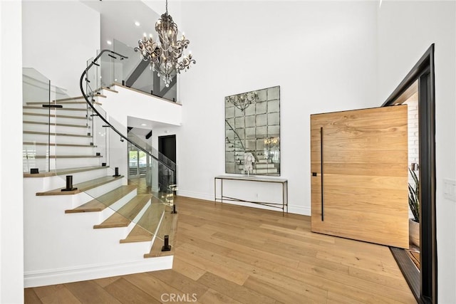 entryway with a towering ceiling, baseboards, hardwood / wood-style floors, and stairs