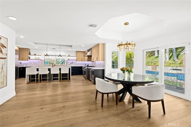 dining room featuring recessed lighting, visible vents, a raised ceiling, and light wood-style floors