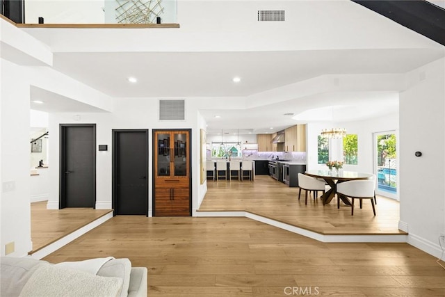 living area with visible vents, elevator, recessed lighting, a notable chandelier, and light wood-type flooring