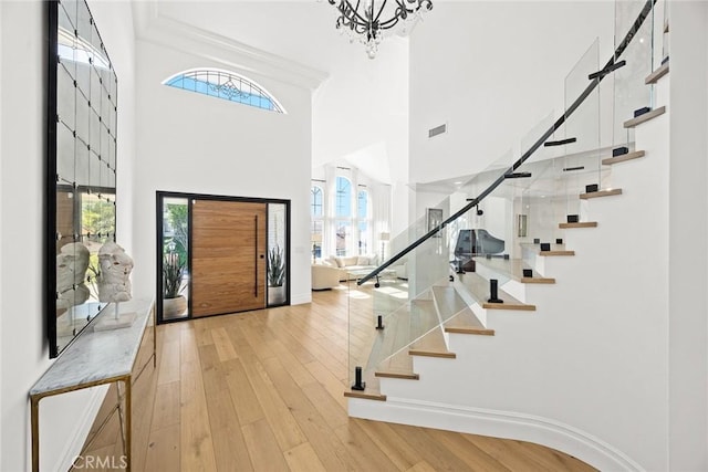 entrance foyer featuring stairs, crown molding, light wood-style flooring, and visible vents