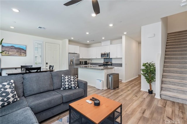 living room with visible vents, light wood finished floors, recessed lighting, ceiling fan, and stairs